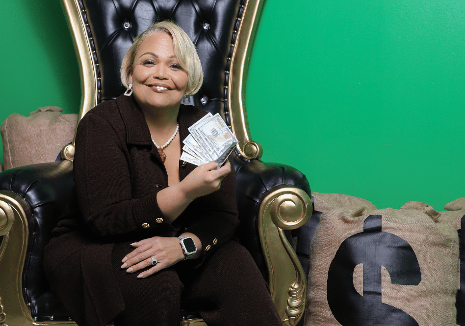 Vicki Wright Hamilton sitting in chair holding cash smiling